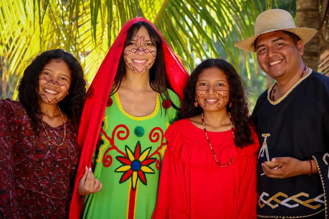 Jóvenes wayuu sonrientes con pintura facial tradicional y vestimentas típicas durante un encuentro intercultural