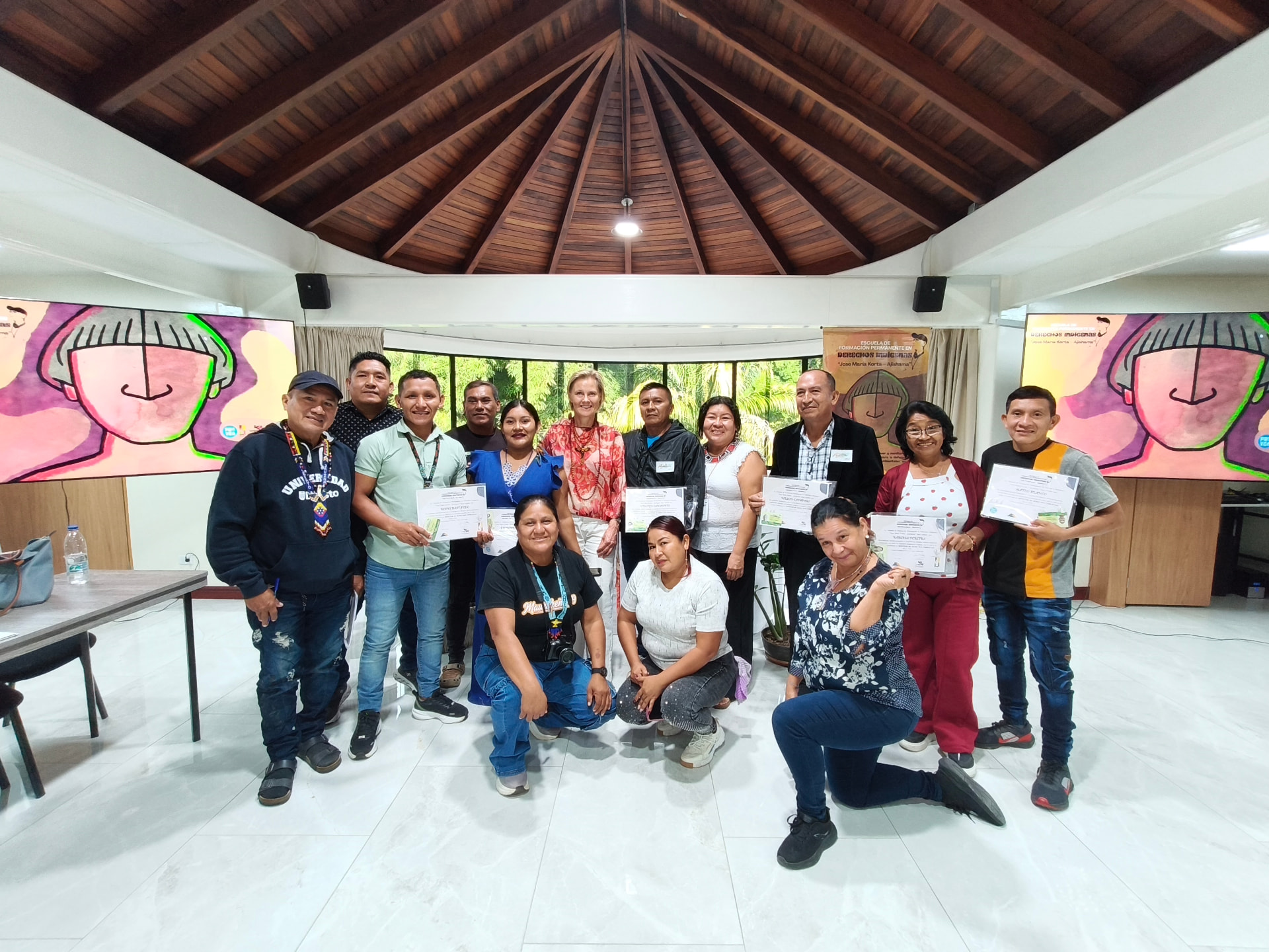 Participantes del curso de promotores indígenas mostrando sus certificados de acreditación en un acto de graduación