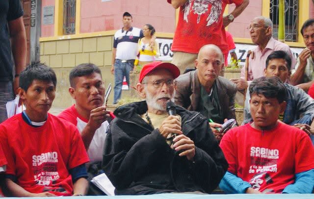 El padre José María Korta interviene con micrófono junto a líderes indígenas en un acto público de defensa de los derechos de los pueblos originarios