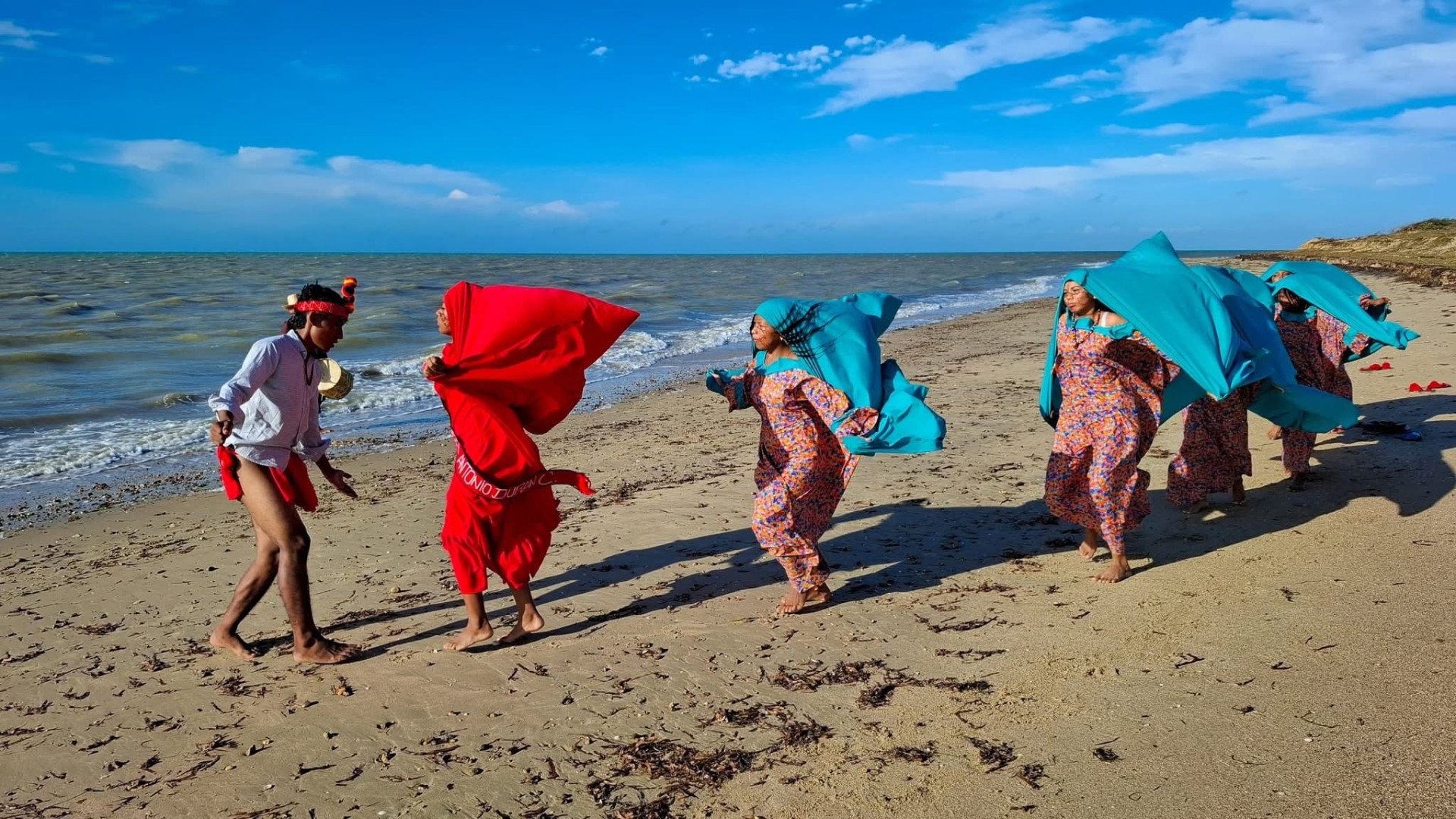 Mujeres y joven del pueblo wayuu vistiendo mantas tradicionales caminan en la playa de la Guajira venezolana durante un encuentro cultural